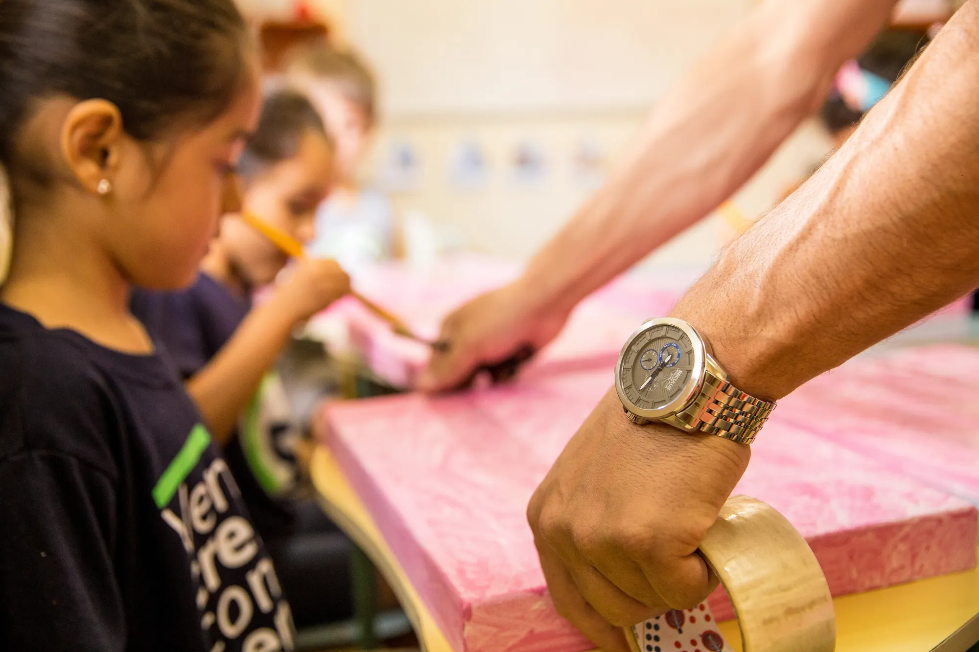Educador ajudando as crianças numa atividade de pintura