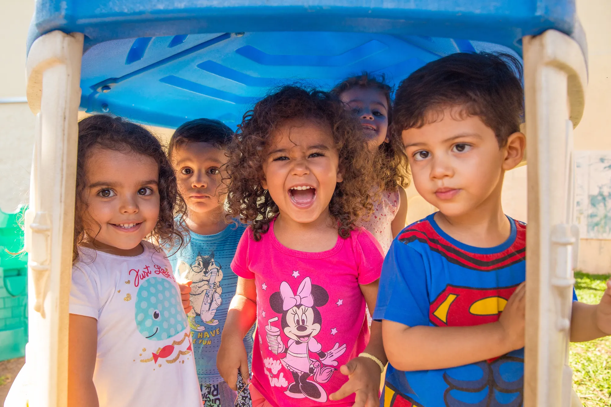 Crianças sorrindo dentro da casinha do parque da escola